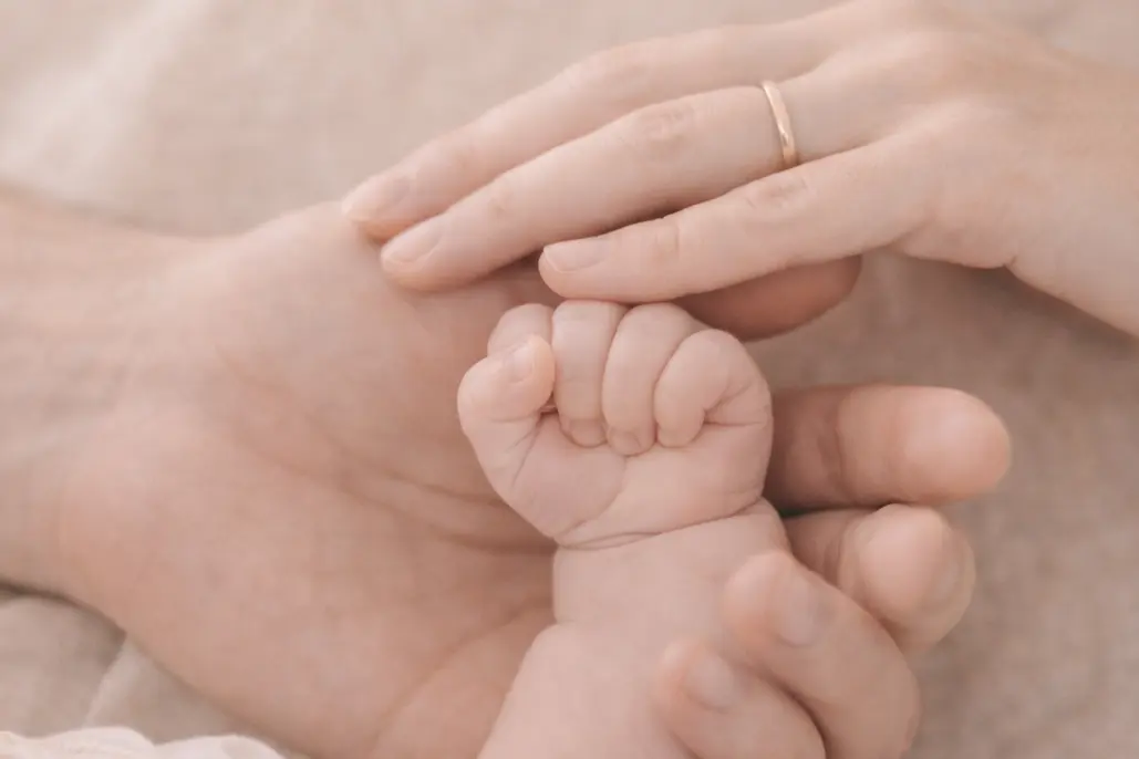 Elternhände halten die kleine Hand ihres Babys